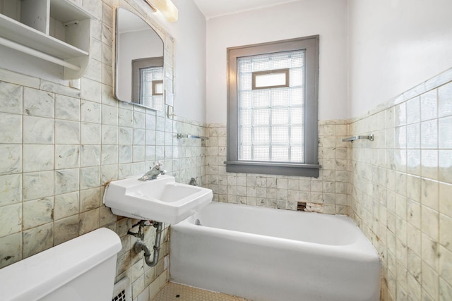 bathroom featuring sink, toilet, a bath, and tile walls