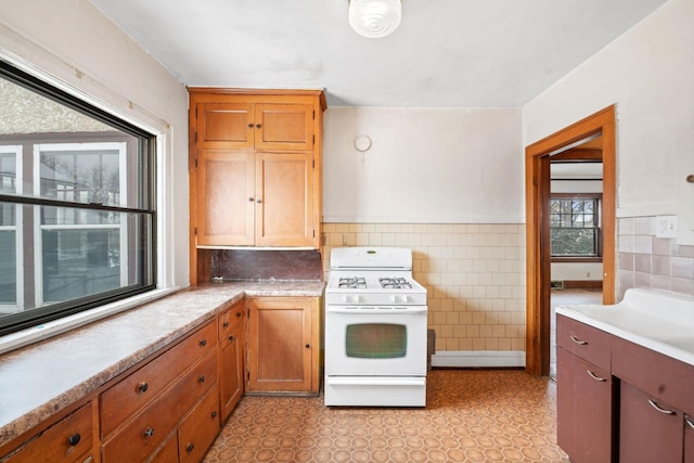 kitchen with white gas stove and tile walls