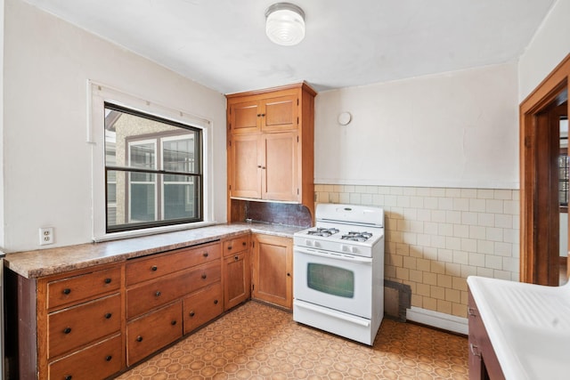 kitchen with white gas stove and tile walls