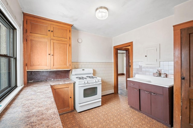 kitchen featuring tile walls, sink, and white gas range oven