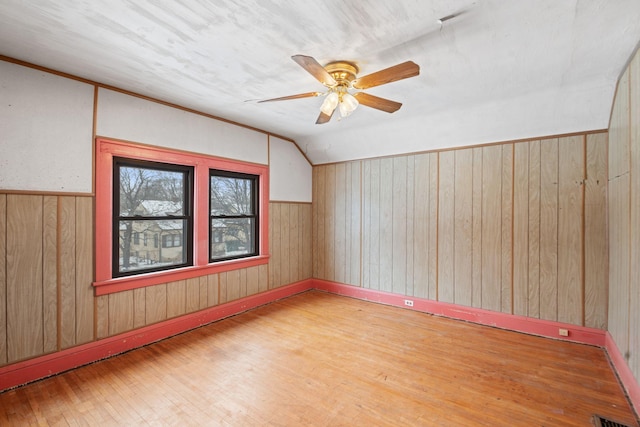 bonus room featuring vaulted ceiling, wooden walls, hardwood / wood-style floors, and ceiling fan