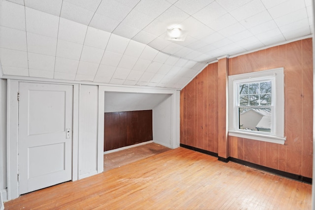 bonus room with hardwood / wood-style flooring, lofted ceiling, and wooden walls