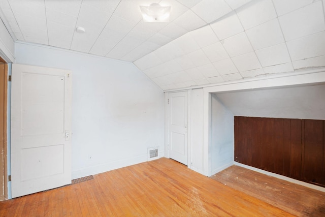 additional living space featuring vaulted ceiling and light wood-type flooring