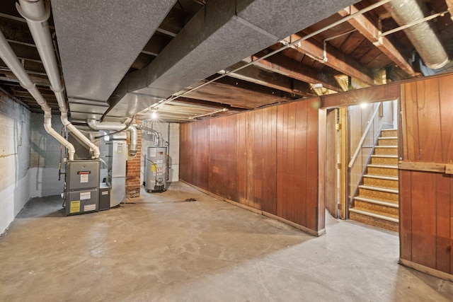 basement with heating unit, wooden walls, and water heater