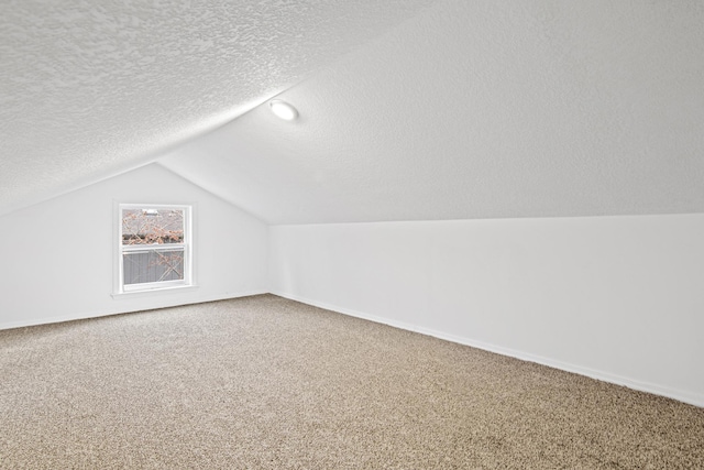 additional living space with vaulted ceiling, carpet flooring, and a textured ceiling