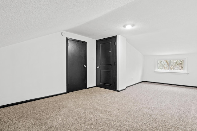 bonus room with vaulted ceiling, carpet, and a textured ceiling