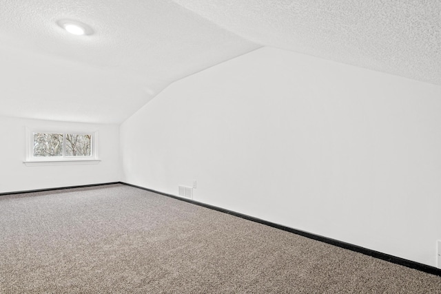 bonus room with carpet, lofted ceiling, and a textured ceiling