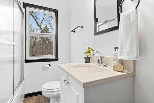 full bathroom with vanity, wood-type flooring, combined bath / shower with glass door, and toilet