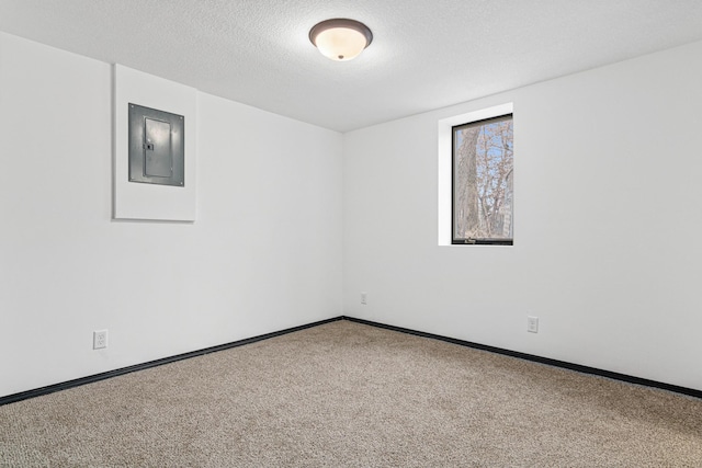 carpeted empty room featuring electric panel and a textured ceiling