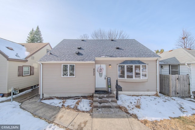 view of front of house with entry steps, a shingled roof, and fence