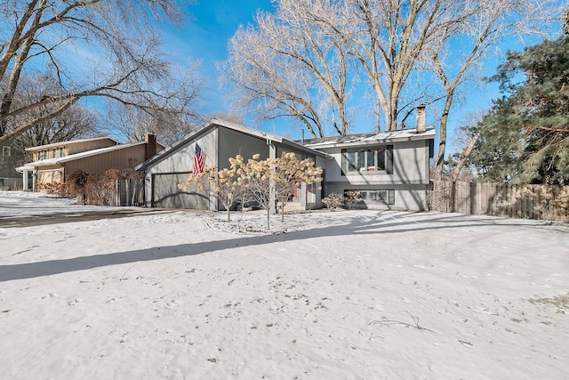 view of front of house with a garage, a chimney, and fence