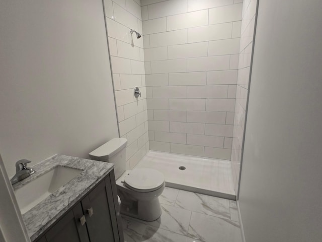 bathroom featuring vanity, tiled shower, and toilet