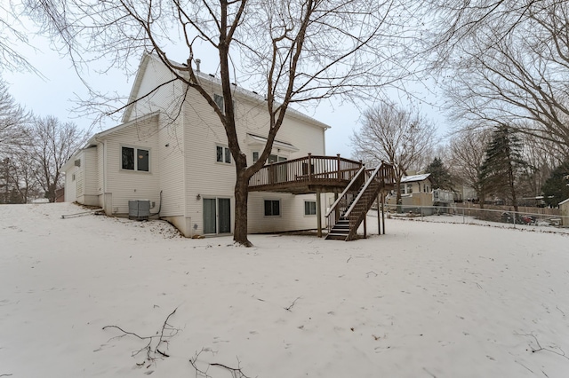 snow covered back of property with central air condition unit and a wooden deck