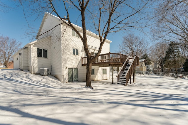 snow covered rear of property with stairs, central AC unit, and a wooden deck