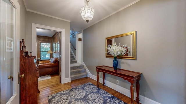 stairway with hardwood / wood-style flooring, ornamental molding, and an inviting chandelier