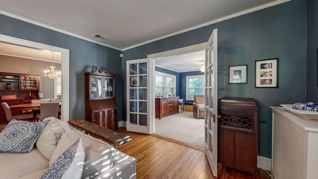 interior space with ornamental molding, french doors, a chandelier, and light wood-type flooring