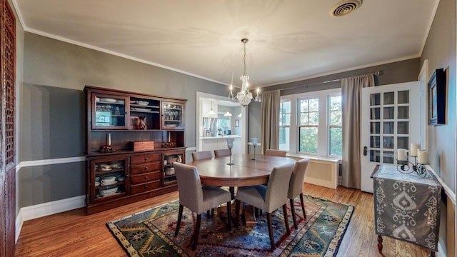 dining area featuring a notable chandelier, wood-type flooring, and ornamental molding