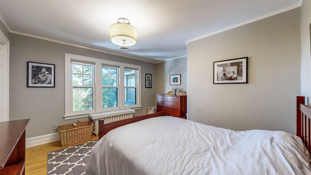 bedroom with radiator heating unit, ornamental molding, and light wood-type flooring