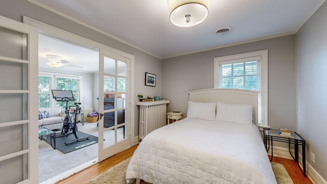 bedroom with multiple windows, hardwood / wood-style floors, and crown molding