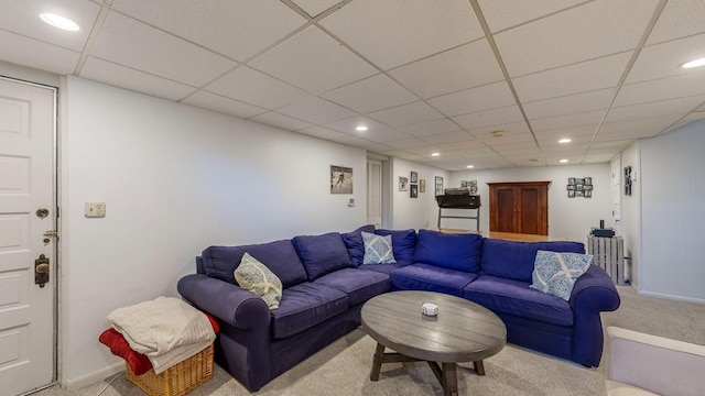 carpeted living room with radiator and a paneled ceiling