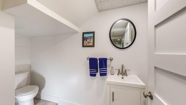 bathroom with vanity, hardwood / wood-style flooring, lofted ceiling, and toilet