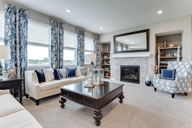 carpeted living room featuring a fireplace, built in features, and a textured ceiling