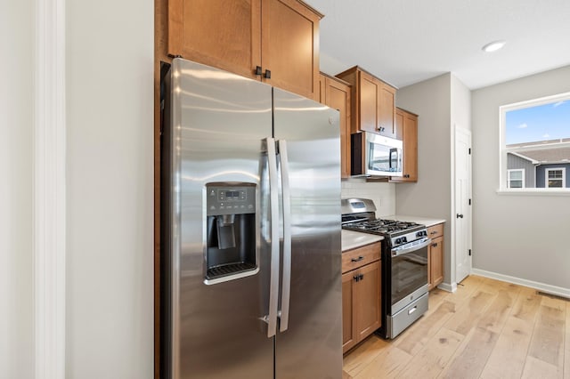 kitchen featuring tasteful backsplash, light hardwood / wood-style flooring, and appliances with stainless steel finishes