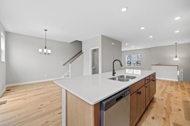 kitchen with sink, hanging light fixtures, light hardwood / wood-style floors, an island with sink, and stainless steel dishwasher