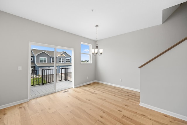 unfurnished dining area featuring a chandelier and light hardwood / wood-style floors