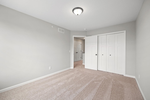 unfurnished bedroom featuring a closet and light carpet