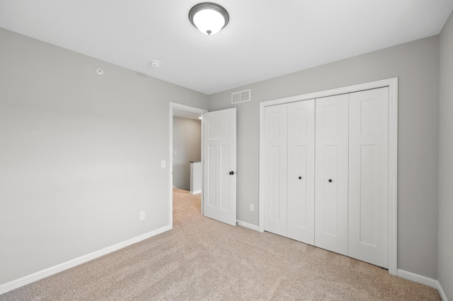 unfurnished bedroom featuring light carpet and a closet