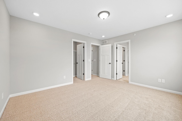 unfurnished bedroom with light colored carpet and a spacious closet