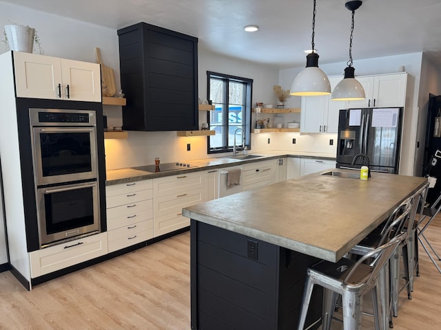 kitchen with sink, a center island, black appliances, white cabinets, and a kitchen bar