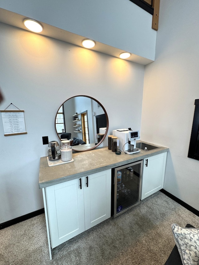 kitchen with white cabinetry, beverage cooler, and dark carpet