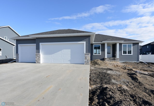 view of front facade featuring stone siding, concrete driveway, and a garage