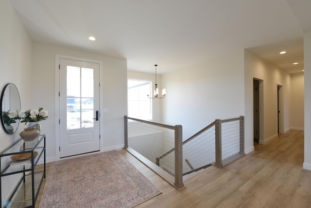foyer with baseboards, a chandelier, light wood-type flooring, and recessed lighting