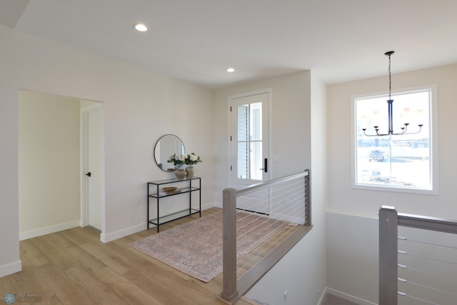 interior space with an upstairs landing, a chandelier, light wood-type flooring, baseboards, and recessed lighting
