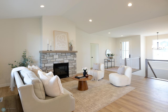 living room featuring recessed lighting, vaulted ceiling, wood finished floors, a stone fireplace, and a chandelier