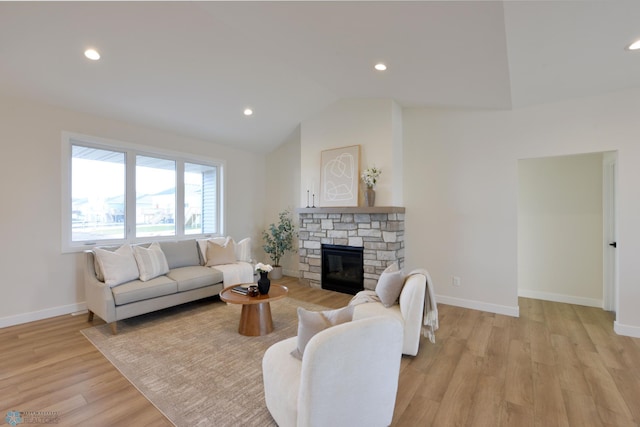 living room featuring vaulted ceiling, baseboards, recessed lighting, light wood-style floors, and a fireplace
