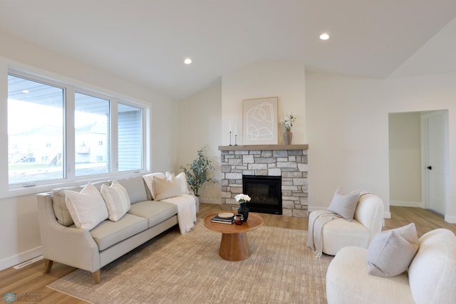 living room with light wood-style flooring, baseboards, recessed lighting, lofted ceiling, and a stone fireplace