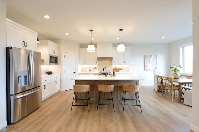 kitchen with backsplash, appliances with stainless steel finishes, light countertops, and light wood-style flooring