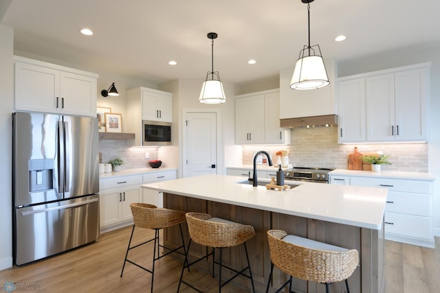 kitchen with light wood finished floors, stainless steel appliances, a breakfast bar area, and tasteful backsplash