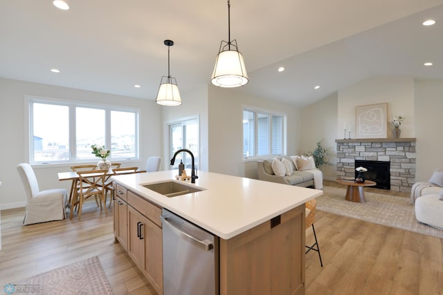 kitchen with a sink, open floor plan, a kitchen island with sink, dishwasher, and light wood-style flooring