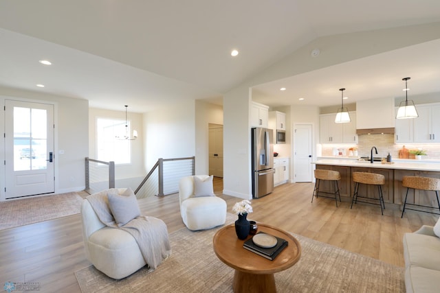 living area featuring light wood-style flooring, baseboards, an inviting chandelier, recessed lighting, and lofted ceiling