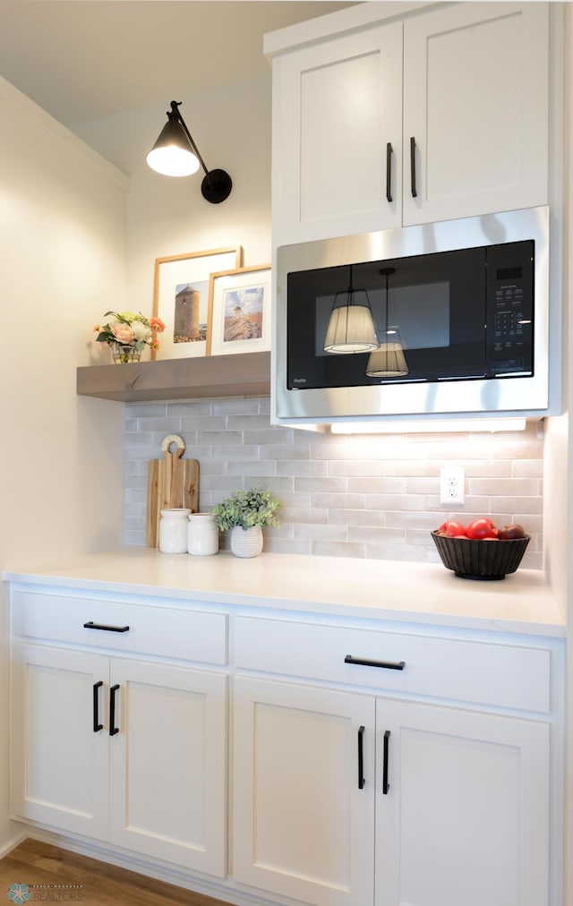 bar featuring stainless steel microwave and tasteful backsplash