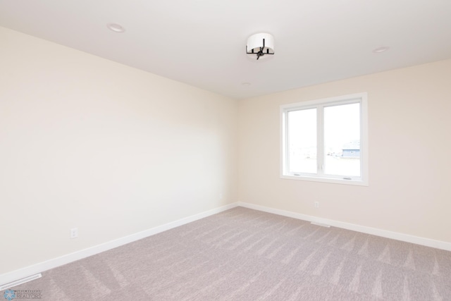 unfurnished room with light colored carpet and baseboards
