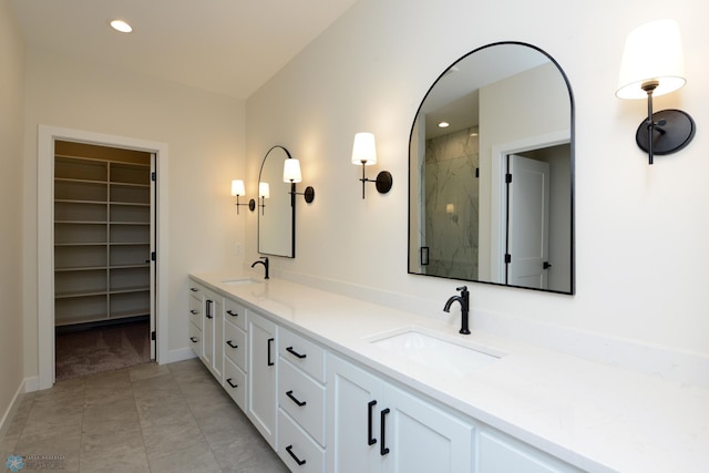bathroom with double vanity, a marble finish shower, a sink, and a walk in closet