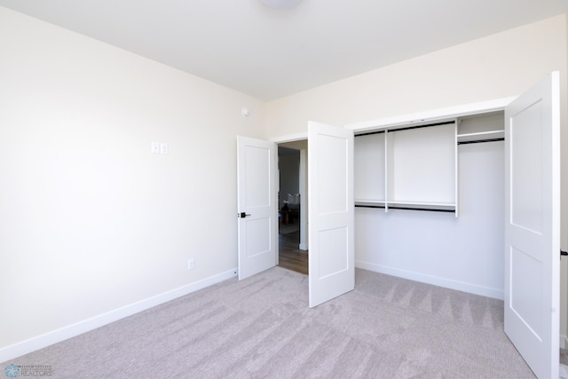 unfurnished bedroom with a closet, baseboards, and light carpet