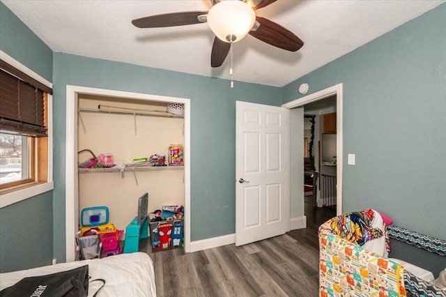 bedroom featuring wood finished floors, ceiling fan, baseboards, and a closet