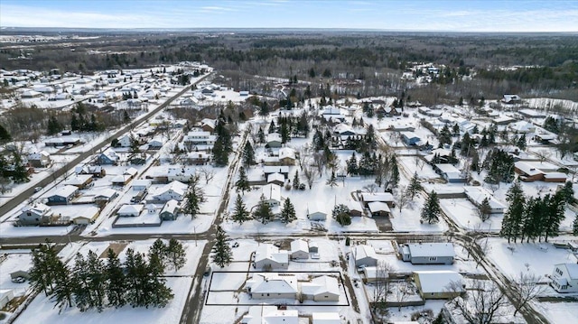 snowy aerial view with a residential view and a wooded view